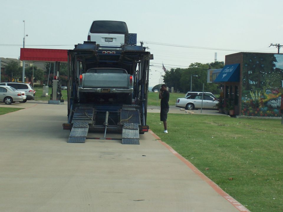 Car hauler trailer rear view with gray Ranchero on lower deck and white van above, ramps down