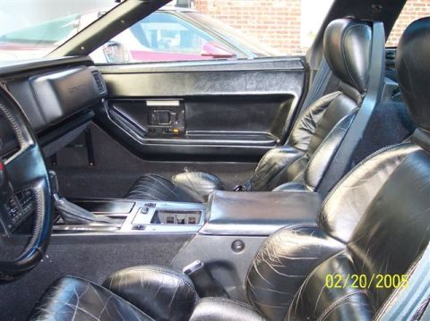 1994 Ford Bronco - Interior view of a car with worn black leather seats and dashboard details. A second vehicle is seen through the side window.