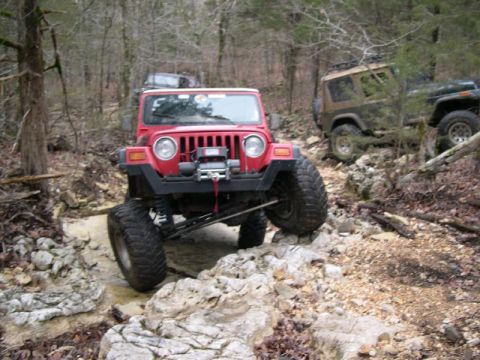 1999 Jeep TJ - Jeeps tackle a challenging off-road trail in a wooded area.