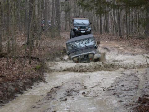 1999 Jeep TJ - Off-roading through a muddy water crossing in a forest.