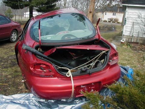 1997 Ford Taurus - Rear view of a damaged 1997 Ford Taurus with its trunk open, parked outdoors.