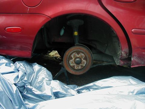 1997 Ford Taurus - Rear brake assembly removed from a red vehicle, showing the rotor and suspension components.