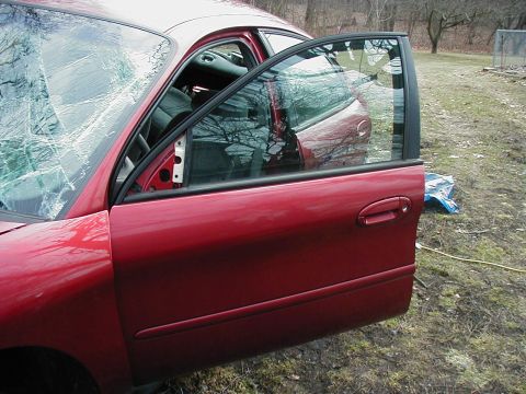 1997 Ford Taurus - This red 1997 Ford Taurus shows significant damage to its windshield and driver's side door.