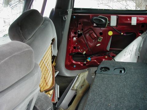 1997 Ford Taurus - The interior of a car is shown with the door panel removed, revealing the inner workings and exposed red metal.