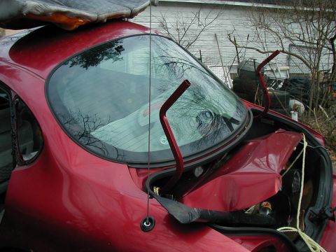 1997 Ford Taurus - The rear of a damaged red sedan shows significant trunk deformation and broken glass.