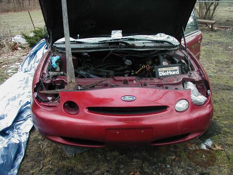 1997 Ford Taurus - A red 1997 Ford Taurus sits with its hood open, revealing the engine bay and a DieHard battery.