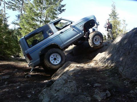 1984 Ford Bronco II - This modified SUV is navigating a challenging rocky terrain with one wheel in the air.