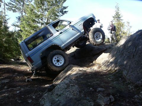 1984 Ford Bronco II - SUV navigates a challenging rocky terrain with two people observing.
