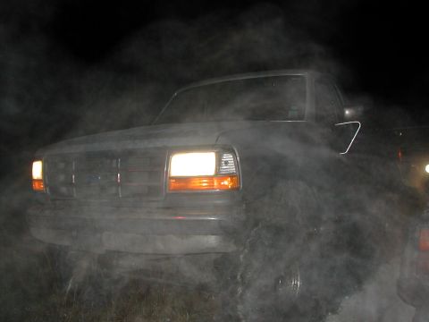 1992 Ford Bronco - A 1992 Ford Bronco is seen at night, enveloped in smoke with its headlights illuminated.