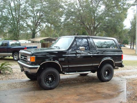 1989 Ford Bronco - This black 1989 Ford Bronco is shown from a 3/4 front angle, chrome accents and custom wheels.