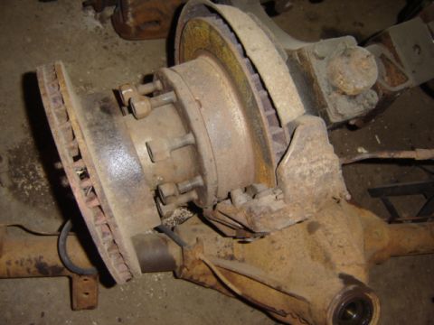 1992 Ford Bronco - This image shows a close-up view of a rusty Ford truck axle assembly, including the brake rotor and hub.