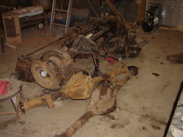 Rusty vehicle axles and differential components scattered on a concrete floor