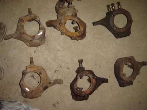 1992 Ford Bronco - Several rusty steering knuckles are laid out on a concrete surface.