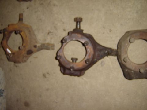 1992 Ford Bronco - Two rusty steering knuckles are shown on a concrete floor.