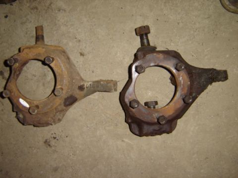 1992 Ford Bronco - Two rusty steering knuckles are shown side-by-side on a concrete floor.