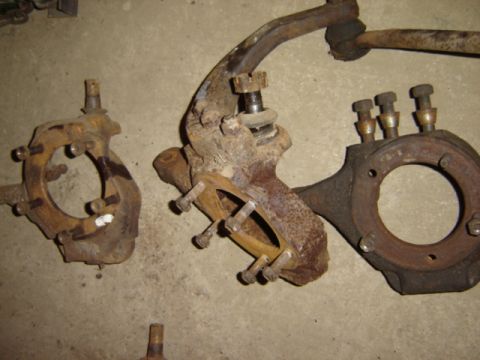 1992 Ford Bronco - Three rusty Dana 44 steering knuckles are laid out on a concrete surface.