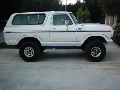 1978 Ford Bronco - Side view of a lifted white 1978 Ford Bronco with chrome wheels and blue accent trim.