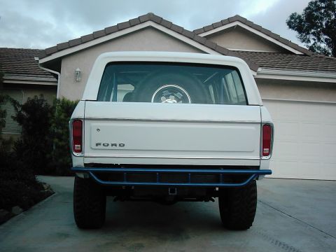 1978 Ford Bronco - Rear view of a white 1978 Ford Bronco a blue aftermarket bumper and a spare tire mounted inside.
