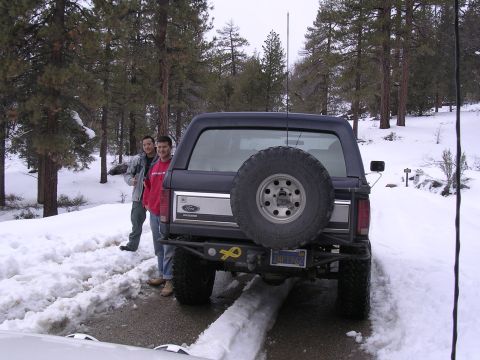 1999 Toyota Tacoma - A dark blue Ford Bronco is parked in the snow with two men standing next to it.