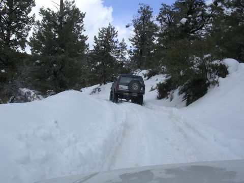 1999 Toyota Tacoma - Toyota Tacoma navigates a snowy mountain path, kicking up snow as it drives.