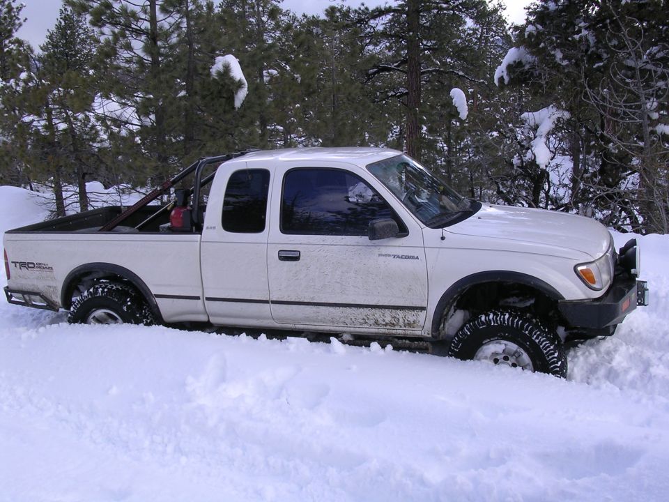 White 1999 Toyota Tacoma stuck in deep snow, side view