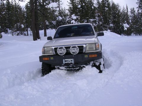 1999 Toyota Tacoma - Toyota Tacoma navigates a snow-covered trail with its front end buried in powder.