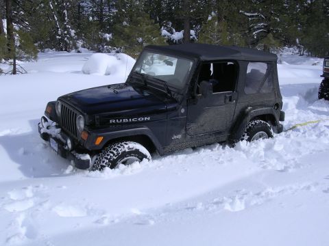 1999 Toyota Tacoma - A black Jeep Wrangler Rubicon is partially buried in snow, with another vehicle visible in the background.