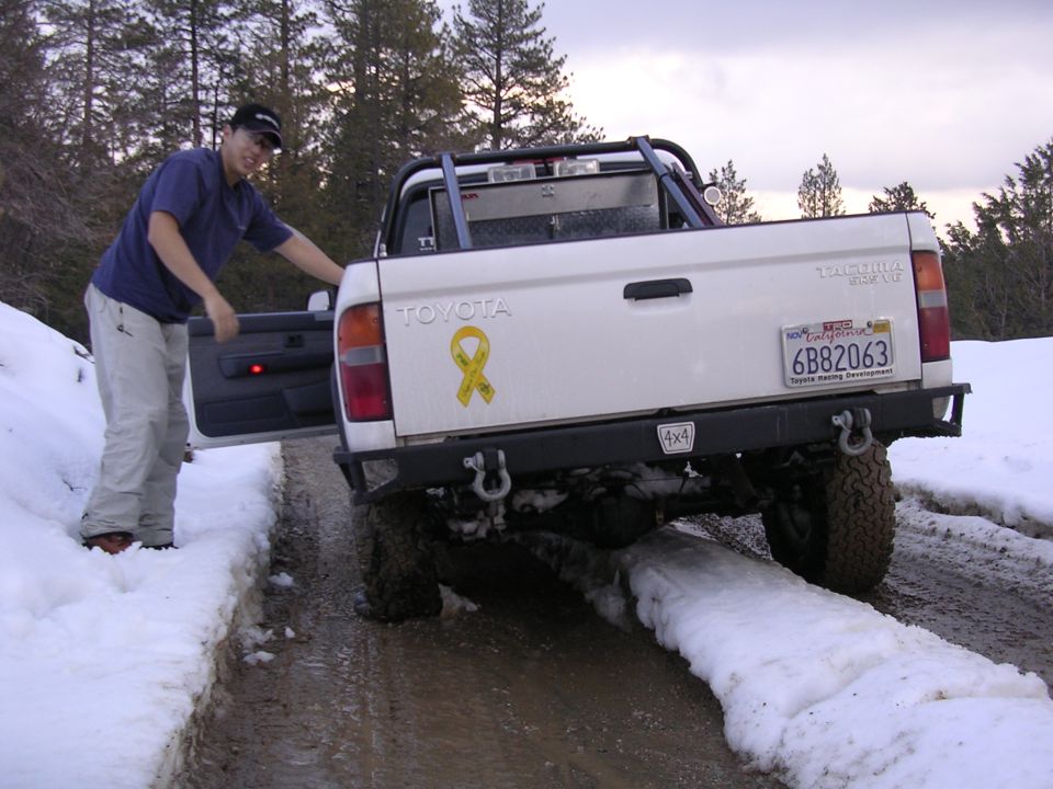 1999 Toyota Tacoma pickup truck with yellow ribbon sticker on tailgate, parked in snow. California license plate 6B82063