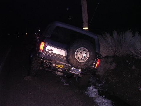 1999 Toyota Tacoma - Ford Bronco parked on an incline at night, with a spare tire on the rear.