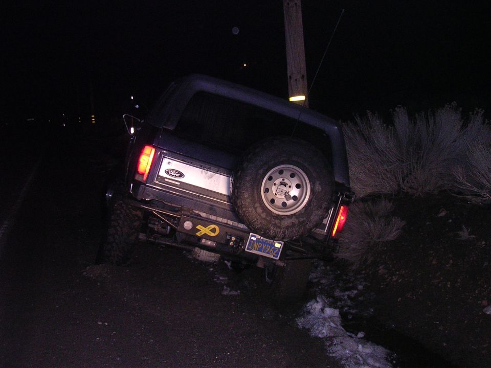 Ford Bronco with spare tire mounted on rear, parked on an incline at night