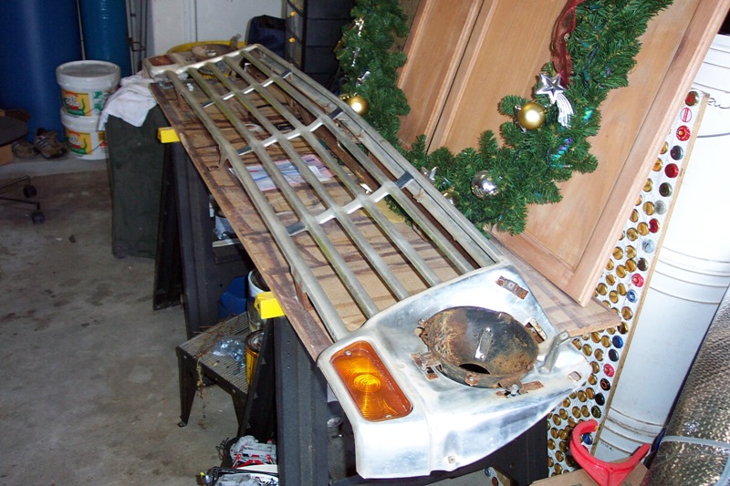Vintage truck grille with amber turn signal resting on a garage workbench