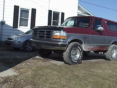 1994 Ford Bronco - Maroon and grey 1994 Ford Bronco parked outside a house with another car behind it.