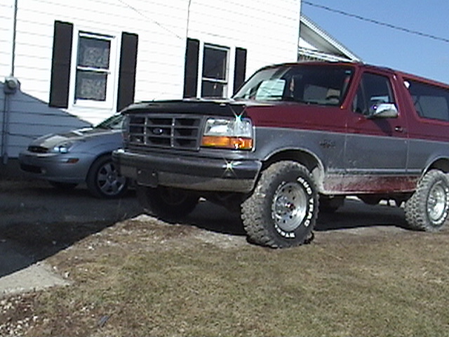 1994 Ford Bronco parked next to a silver sedan