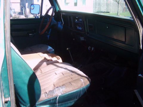 1978 Ford Bronco - The interior of an older vehicle shows worn seats and a dashboard with a radio.