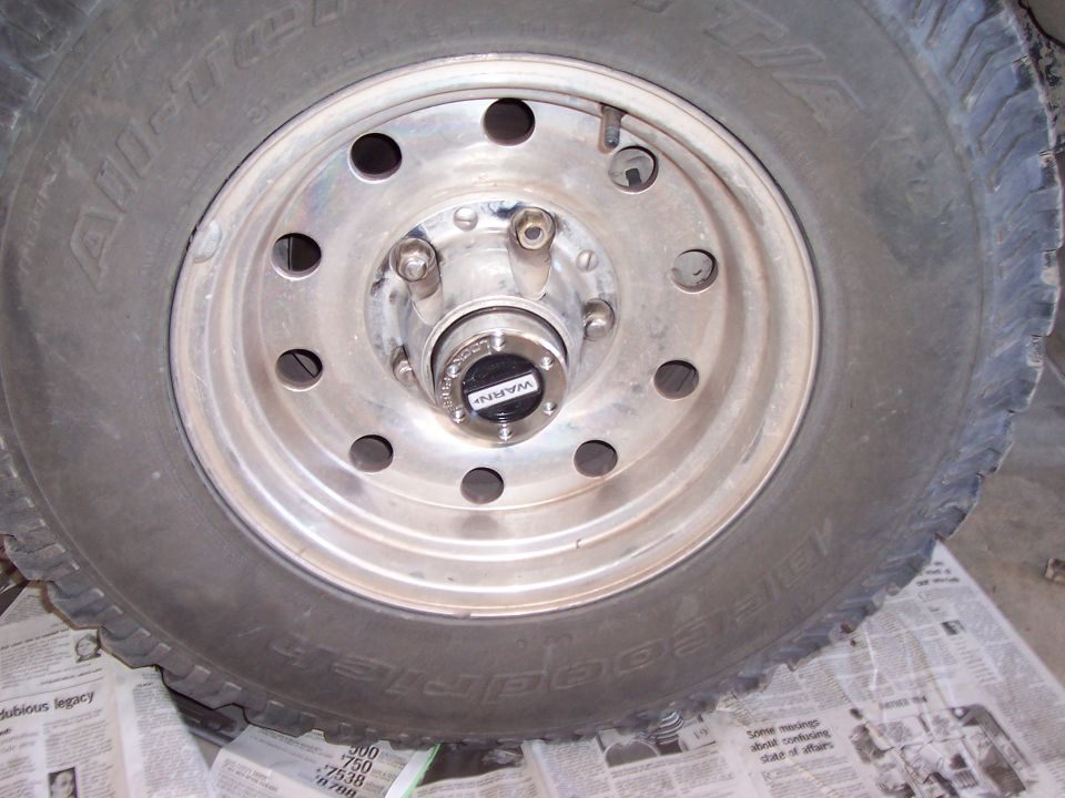Silver steel wheel with locking hub center and All-Terrain T/A tire resting on newspaper