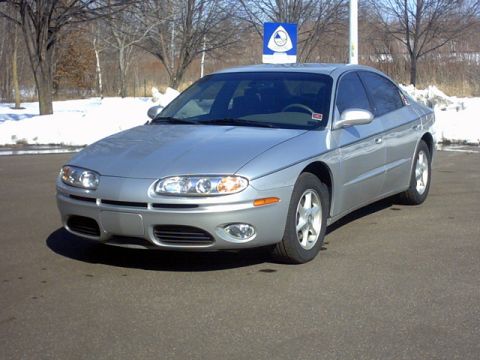 2002 Oldsmobile Aurora - Silver sedan with a distinctive grille and headlight design is shown from the front 3/4 angle.