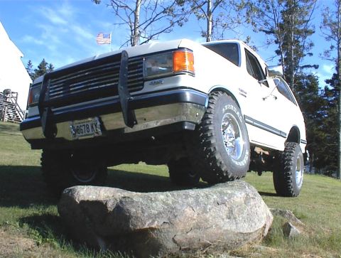 1988 Ford Bronco - This white SUV is positioned on a large rock, its off-road capabilities.