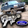 1993 Ford Bronco - A dark blue Ford Bronco navigates a rocky, muddy terrain.