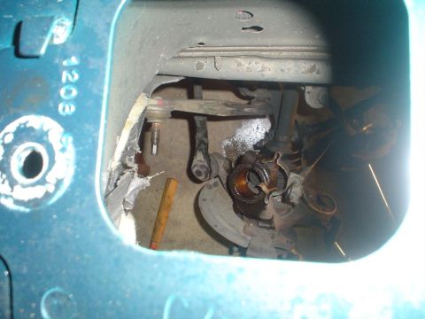 1993 Ford Taurus - Damaged vehicle suspension components are visible, with a wooden dowel nearby and teal painted metal framing.