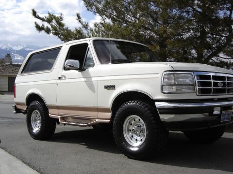 1995 Ford Bronco - This 1995 Ford Bronco is shown in a three-quarter front view, highlighting its white exterior and tan trim.