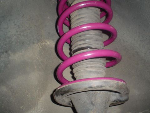 1993 Ford Taurus - This is a close-up view of a vehicle's suspension component, specifically a shock absorber with a bright pink coil spring.
