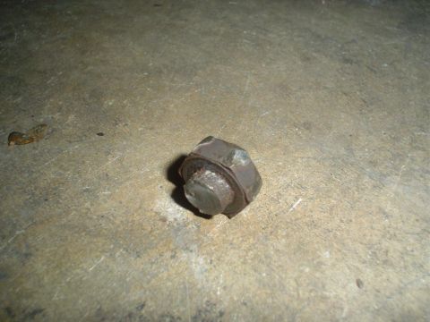 1993 Ford Taurus - A single rusted bolt and nut rests on a concrete surface, likely a spare part.