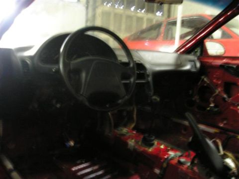 1994 Ford Probe - Stripped interior of a 1994 Ford Probe, with another vehicle visible in the background.
