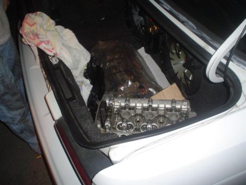 1993 Ford Taurus - Engine cylinder head with valves and timing chain is visible in the trunk of a white car.