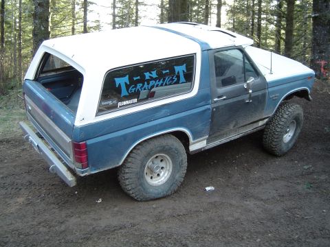 1989 Ford Bronco - This Ford Bronco, likely from the 1980s, is seen from a three-quarter front angle on a dirt surface.