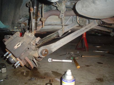 1993 Ford Taurus - Mechanic's tools and a spray can surround the disassembled rear suspension of a vehicle.