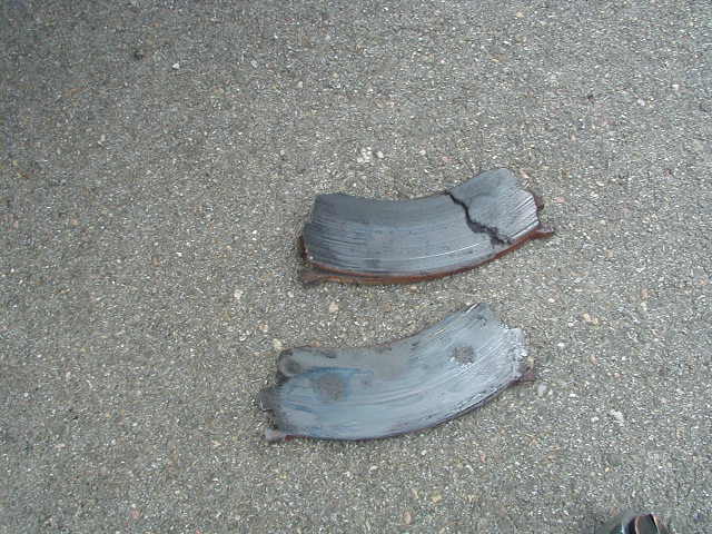 Two broken brake rotors on asphalt. One rotor is cracked