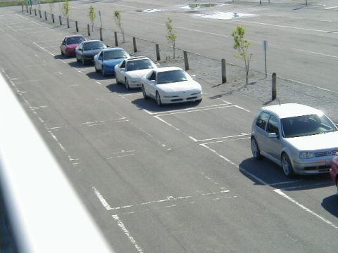 1993 Ford Probe - A row of vehicles are parked in an outdoor lot on a sunny day.