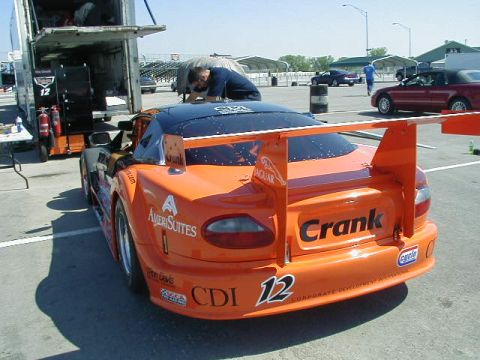 1993 Ford Probe - An orange race car with a prominent rear wing and sponsor decals is parked on a track.