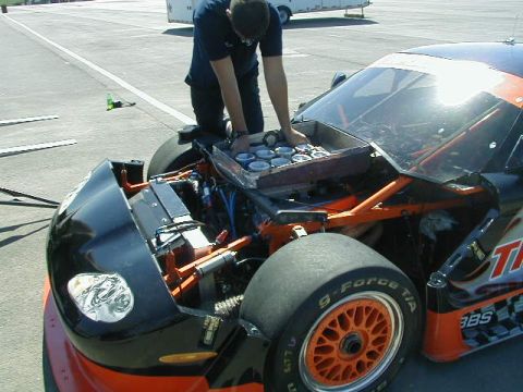 1993 Ford Probe - A person is tending to the engine of a race car, with the hood open to reveal the internal mechanics.